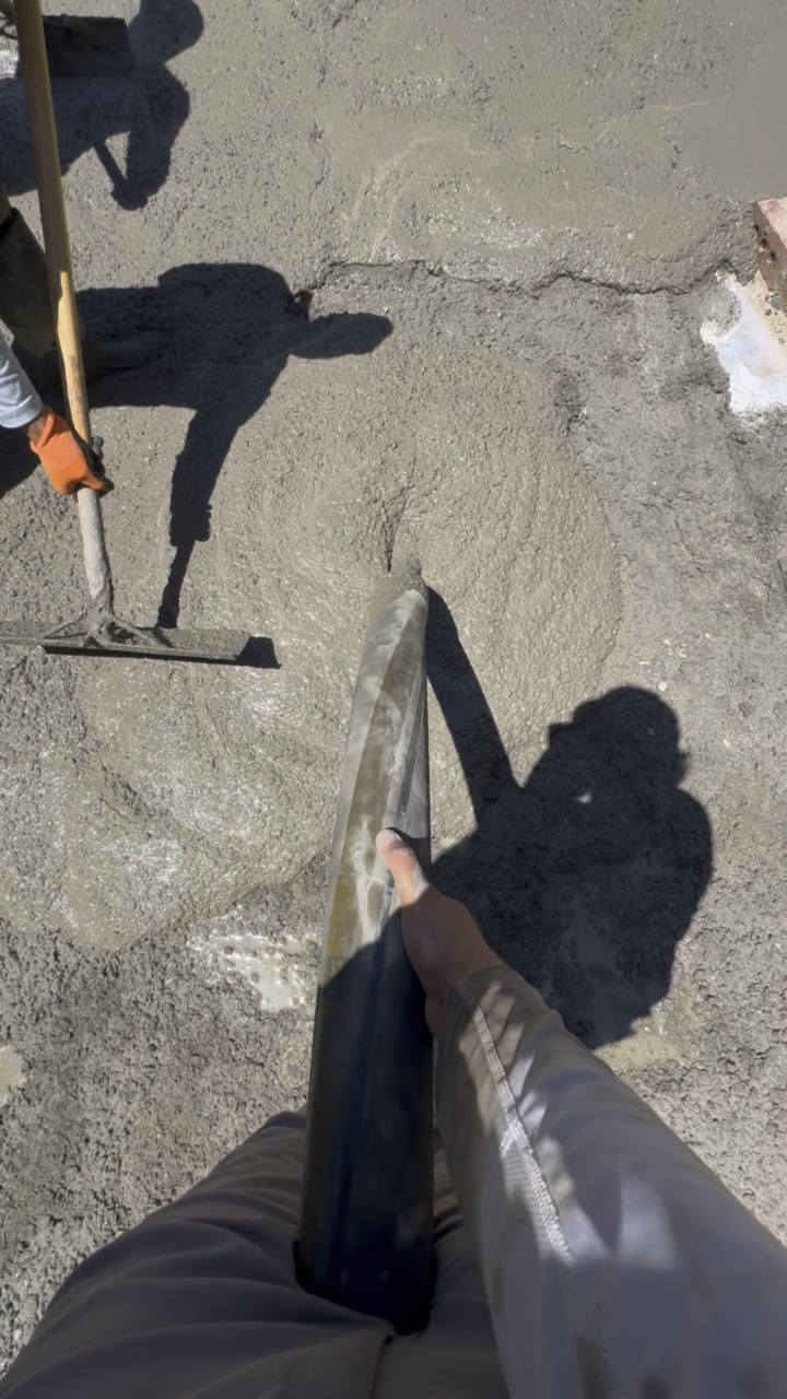 Worker raking concrete during pour